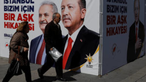 People walk past an AK Party campaign tent with pictures of Turkish President Tayyip Erdogan and his party's candidate for mayor in Istanbul Binali Yildirim for the upcoming local elections in Istanbul