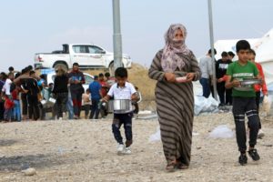 Syrian displaced families, who fled violence after the Turkish offensive in Syria, get food from Barzani charity at a refugee camp in Bardarash on the outskirts of Dohuk